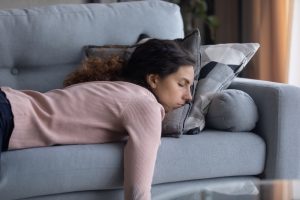 Exhausted,Young,Caucasian,Woman,Lying,On,Comfortable,Sofa,In,Living